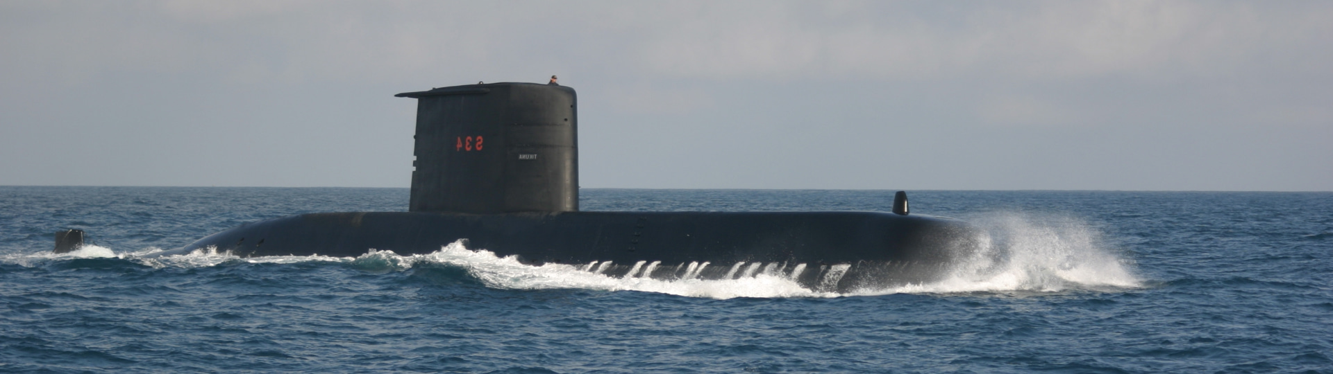 Submarino negro 831 navegando en superficie con espuma blanca