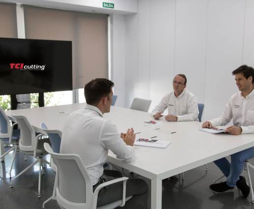 Reunión de asesoramiento en sala de juntas con logo TCI Cutting en pantalla