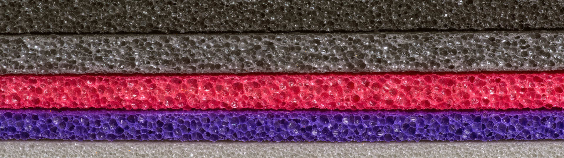 Capas de espuma porosa en gris, rosa y violeta apiladas