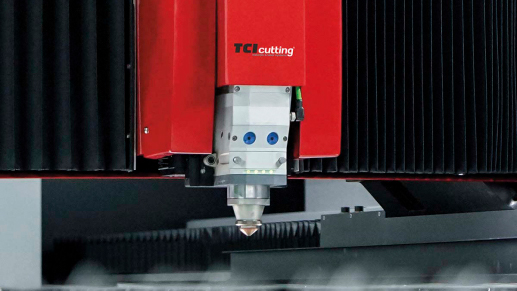 TCI Cutting laser head with copper nozzle and green status LEDs over the cutting bed